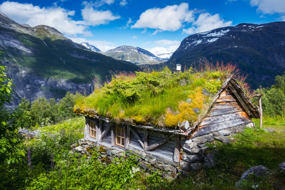 Typical norwegian old wooden houses with grass roofs near Sunnylvsfjorden fjord and famous Seven Sisters waterfalls, western Norway.